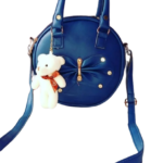 Royal blue round sling bag with teddy bear charm, decorative bow and long shoulder strap.